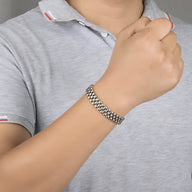 Bracelet magnétique en germanium argenté tressé porté au poignet d'un homme en polo gris clair.