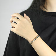 Bracelet magnétique en titane argenté avec maillons larges porté à un poignet féminin.