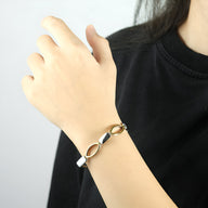 Bracelet magnétique en titane argenté et or, design moderne avec maillons ovales, porté au poignet féminin.