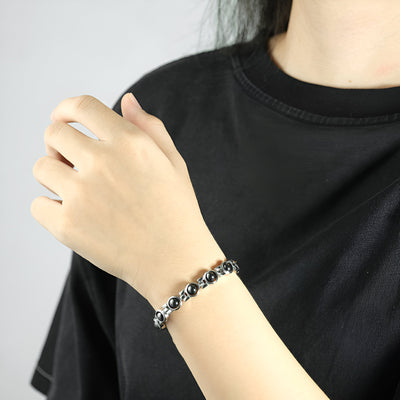 Bracelet magnétique en titane argenté à maillons arrondis porté au poignet féminin.