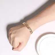 Bracelet magnétique en titane or rosé à maillons larges porté au poignet masculin.