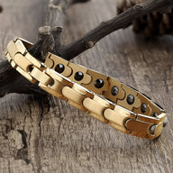 Bracelet magnétique homme en titane couleur or avec maillons larges et pastilles noires visibles à l'intérieur.