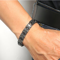 Bracelet magnétique en titane gris foncé avec maillons gravés et fermoir discret pour homme.