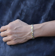 Bracelet magnétique fin en titane bicolore or et argent pour homme, modèle Arne, sur poignet mâle.