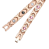 Bracelet magnétique en titane or rosé avec zirconiums roses et éléments magnétiques noirs et blancs.
