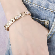 Bracelet en titane or rosé avec zircons roses en forme de fleurs, style magnétique pour femme.