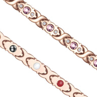 Bracelet magnétique en titane or rosé avec zirconiums roses et pierres colorées intégrées.