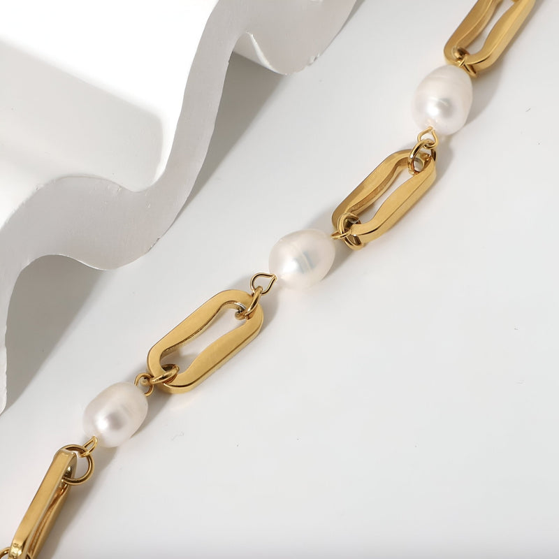 Bracelet en acier inoxydable doré avec maillons ovales et perles d'eau douce blanches, style élégant.