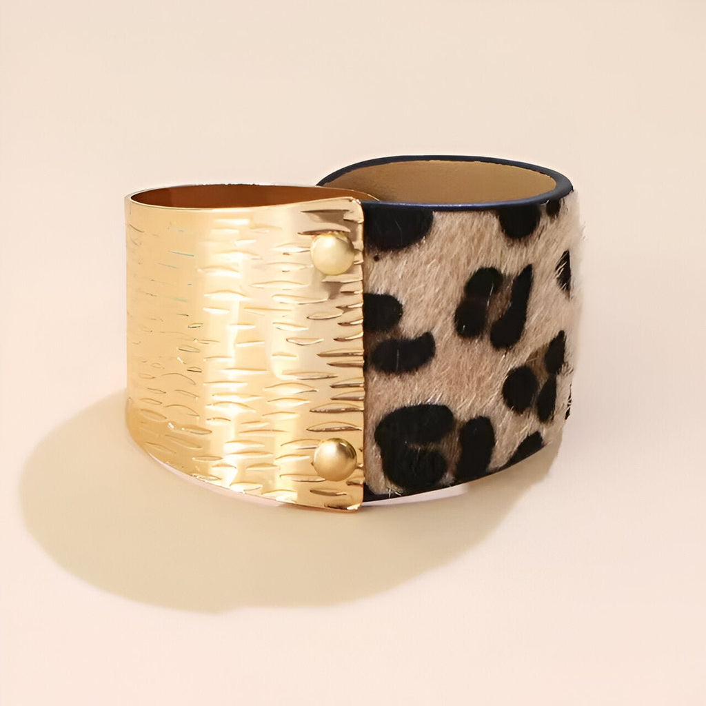 Bracelet manchette femme avec face léopard beige et face métal doré texturé à rivets.