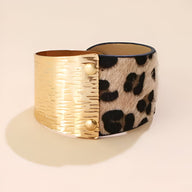 Bracelet manchette femme avec face léopard beige et face métal doré texturé à rivets.