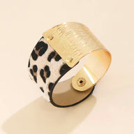 Bracelet manchette beige avec motif léopard noir et doré, fermeture pression métallique dorée.