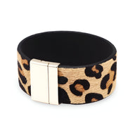 Bracelet manchette large en cuir beige à motif léopard avec fermeture métallique argentée.