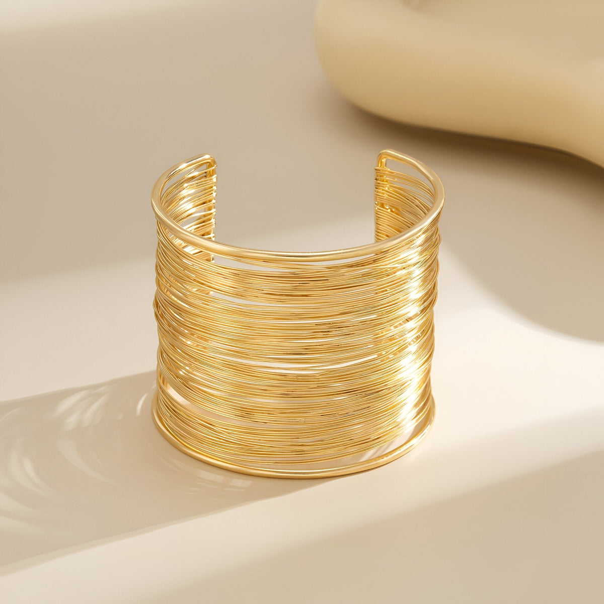 Bracelet manchette doré à multiples branches fines en alliage métallique lisse et brillant.