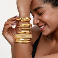 Bracelet manchette doré en acier inoxydable au design texturé moderne porté sur le poignet.