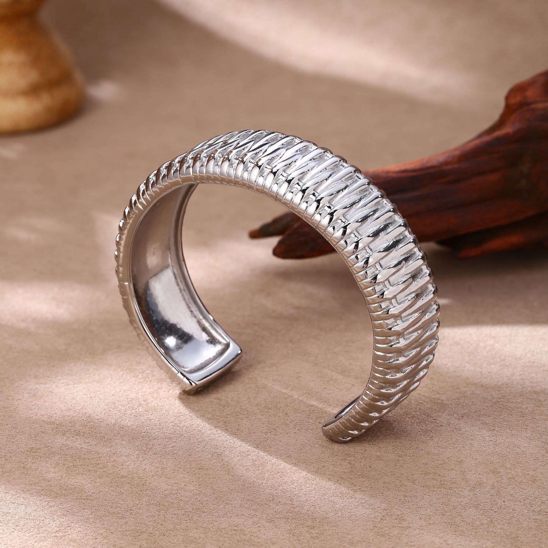 Bracelet manchette argenté en acier inoxydable avec texture tressée moderne en demi-cercle.