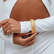 Bracelet manchette doré texturé en acier inoxydable, large, forme rigide, design contemporain élégamment griffé.