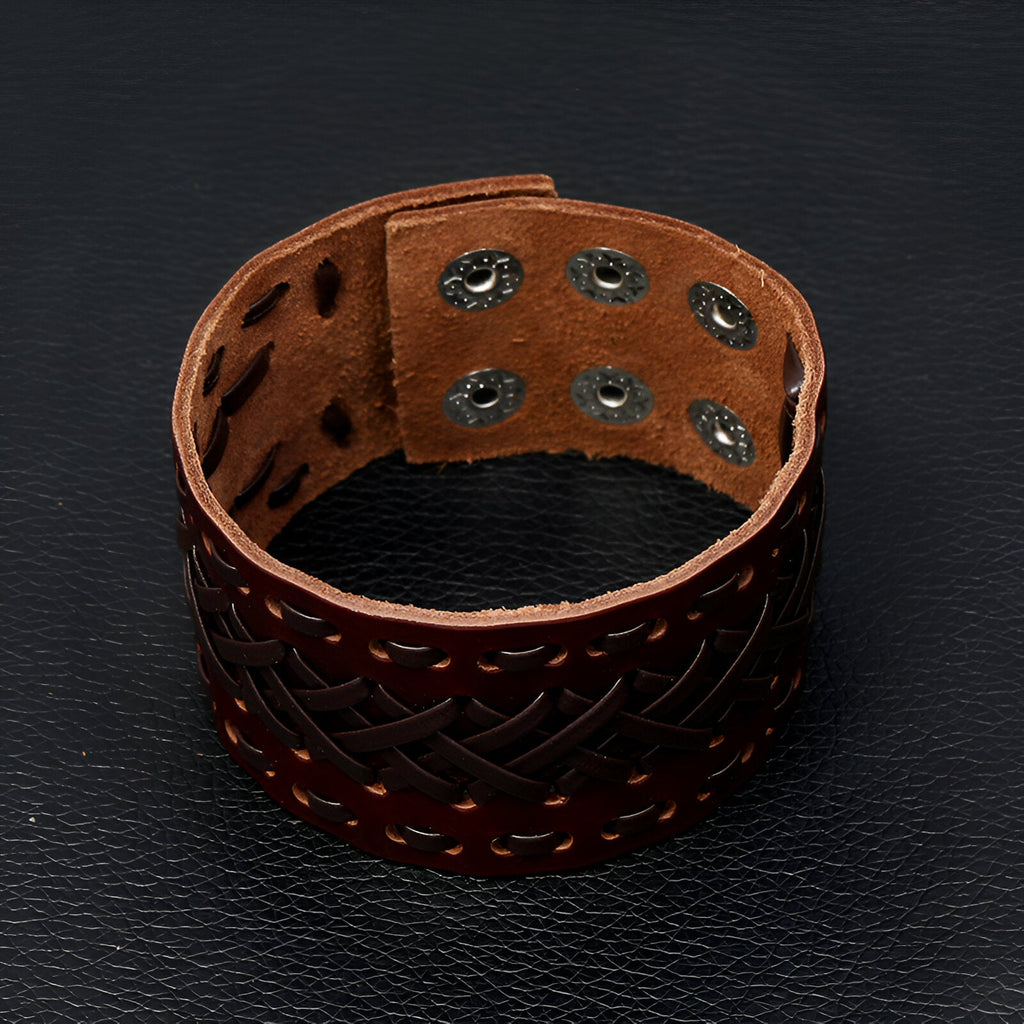 Bracelet manchette en cuir marron tissé avec fermeture à pression métallique double.