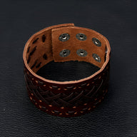 Bracelet manchette en cuir marron tissé avec fermeture à pression métallique double.