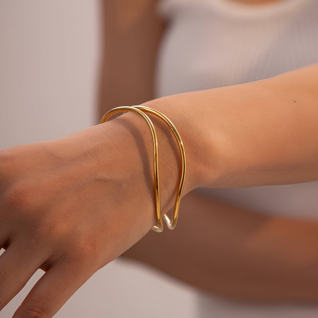 Bracelet manchette en titane plaqué or, design fluide et moderne, finition brillante.