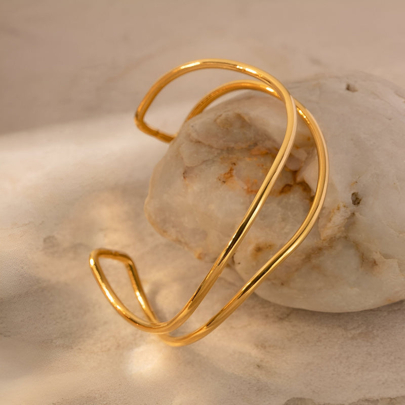Bracelet manchette en titane plaqué or à double bande incurvée au design élégant et épuré.
