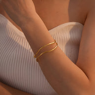 Bracelet manchette Mirabel en titane plaqué or, design fin et contemporain sur peau bronzée.