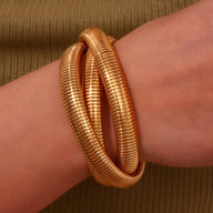 Bracelet manchette duo doré à effet serpent enroulé autour du poignet féminin.