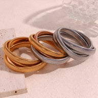 Ensemble trio de bracelets manchettes serpent en métal doré, argenté et cuivre, finition texturée brillante.