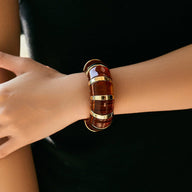 Bracelet manchette épais en acrylique marron avec inserts dorés, style chic et contemporain.
