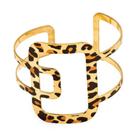 Bracelet manchette en métal doré orné d'un motif léopard stylisé au centre.