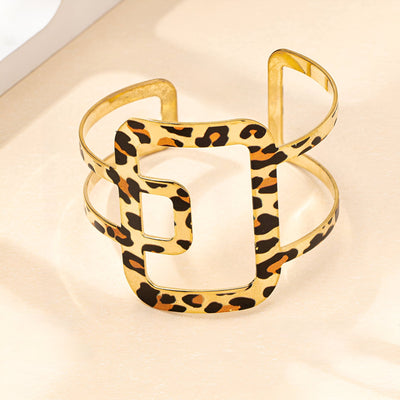 Bracelet manchette doré en métal or avec motif léopard et forme géométrique ajourée.