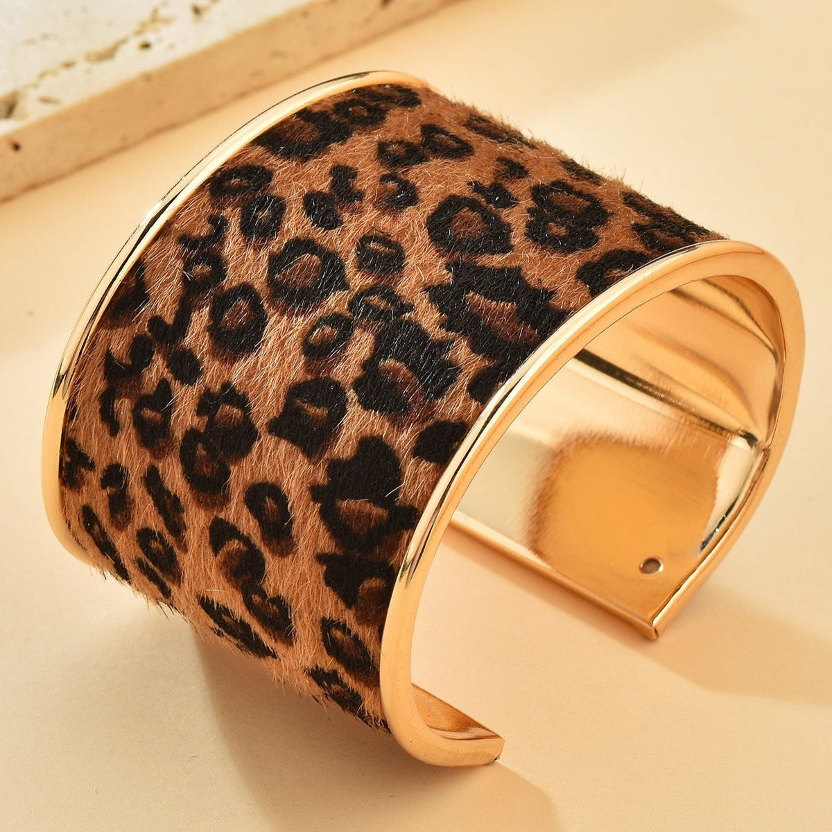 Bracelet manchette large en métal doré avec motif léopard sur tissu marron et noir.