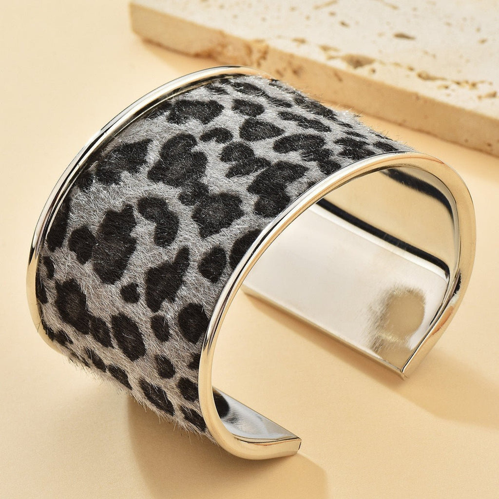 Bracelet manchette large en métal argenté avec motif léopard noir et gris texturé.