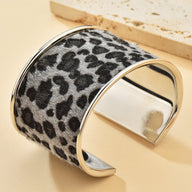 Bracelet manchette large en métal argenté avec motif léopard noir et gris texturé.