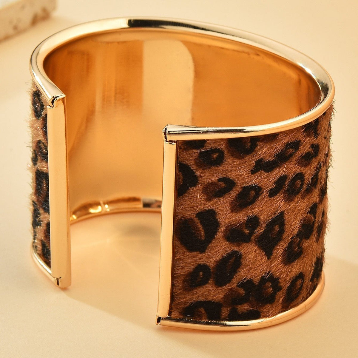 Bracelet manchette doré avec motif léopard en fourrure synthétique et bords lisses polis.