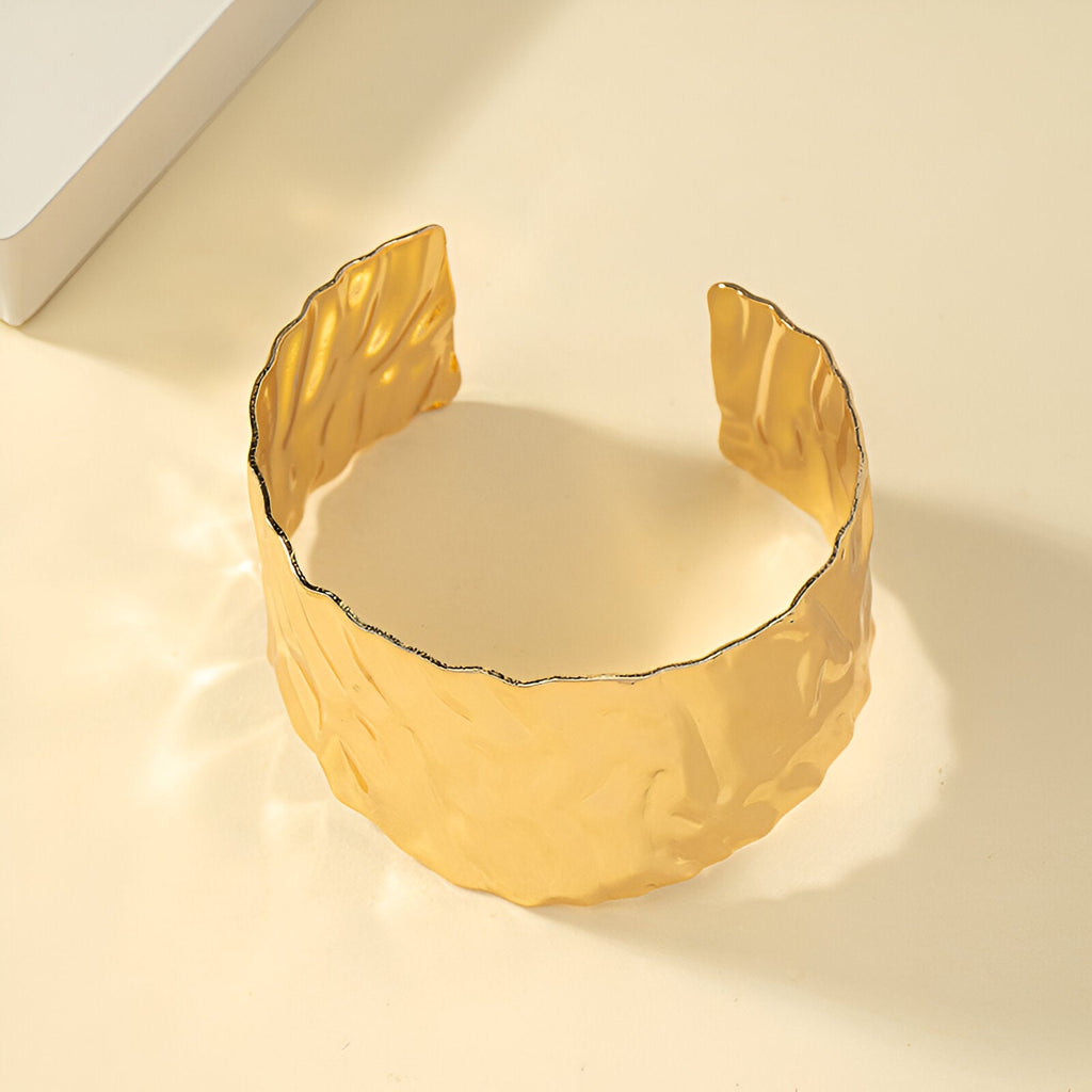 Bracelet manchette or ondulé en alliage métallique avec finition texturée brillante.