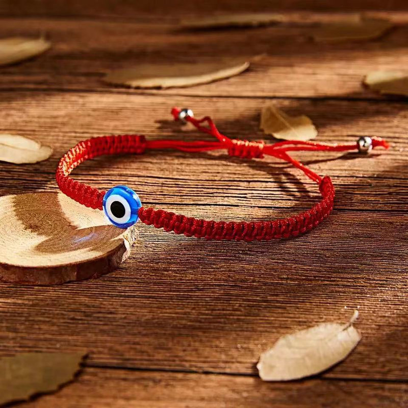 Bracelet rouge en fil ciré avec pendentif œil bleu et blanc, design tressé ajustable.