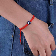Bracelet fil rouge ciré avec perle œil bleu et blanc, style minimaliste, ajustable.