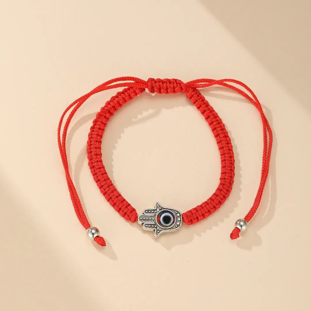 Bracelet fil rouge ciré avec main de Fatma et œil protecteur en métal argenté.