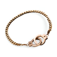 Bracelet en acier inoxydable or rosé avec menottes détaillées et chaîne épaisse.