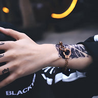 Bracelet menottes en acier inoxydable couleur or rosé avec chaîne fine et fermoir unique.