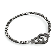Bracelet menottes en acier inoxydable gris avec chaîne maillons plats et fermoir menottes stylisé.