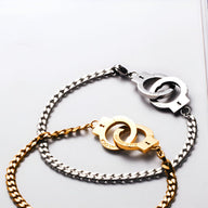 Bracelet menottes en acier inoxydable, chaîne argentée et or avec fermoirs menottes entrelacées.