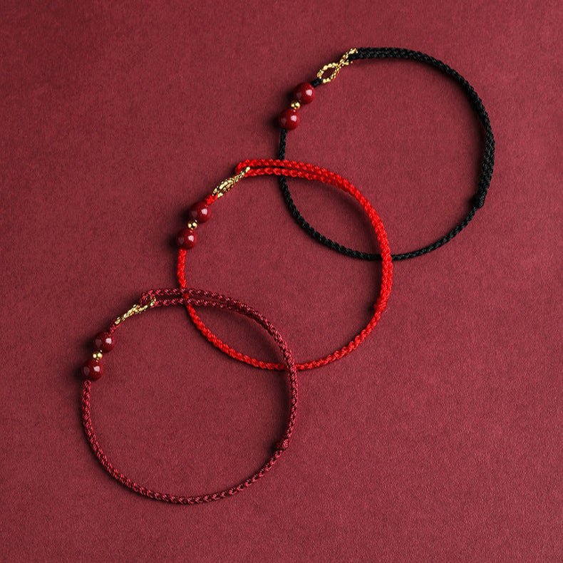 Trois bracelets minimalistes en fil ciré bordeaux, rouge, noir avec pierres de cinabre et motif infini doré.