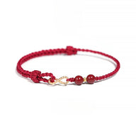 Bracelet rouge en fil ciré avec motif infini en métal doré et deux pierres rondes de cinabre.