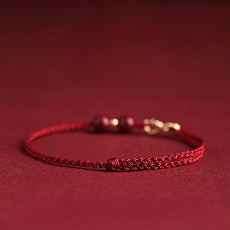 Bracelet fin rouge en fil ciré tressé avec motif infini en métal et petites perles de cinabre.