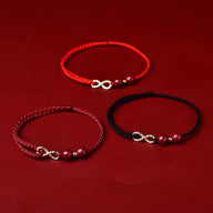 Trois bracelets minimalistes en fil ciré rouge, bordeaux et noir avec symbole infini en métal doré et pierres de cinabre.