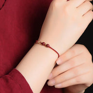 Bracelet fin bordeaux en fil ciré avec pierres de cinabre et petit motif infini en métal argenté.