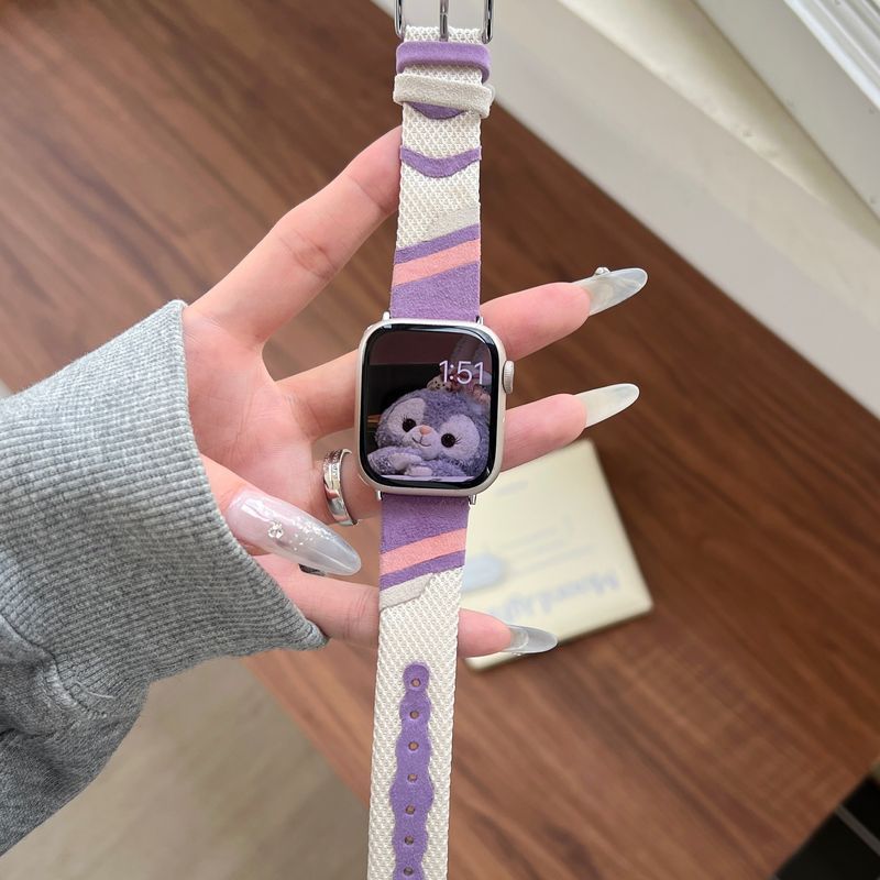 Bracelet montre Apple Watch en toile tissée rose et violet avec intérieur cuir doux, style ludique et boucles ajustables.