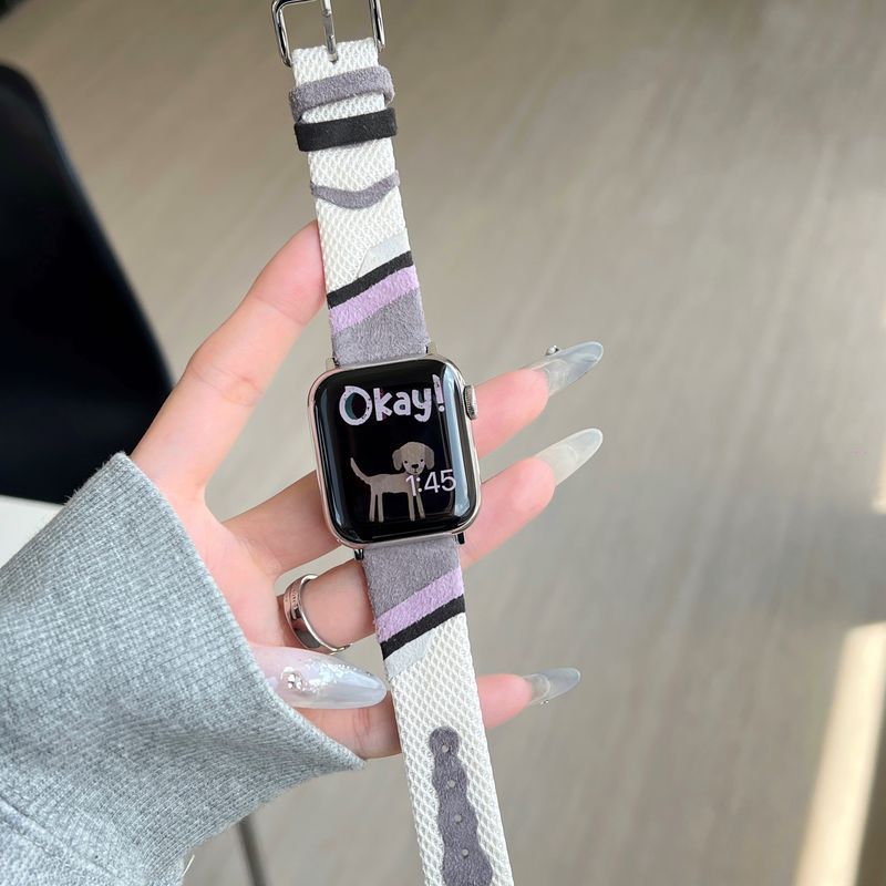 Bracelet Apple Watch en toile tissée beige à motifs noirs et violets, intérieur cuir doux, boucle argentée.