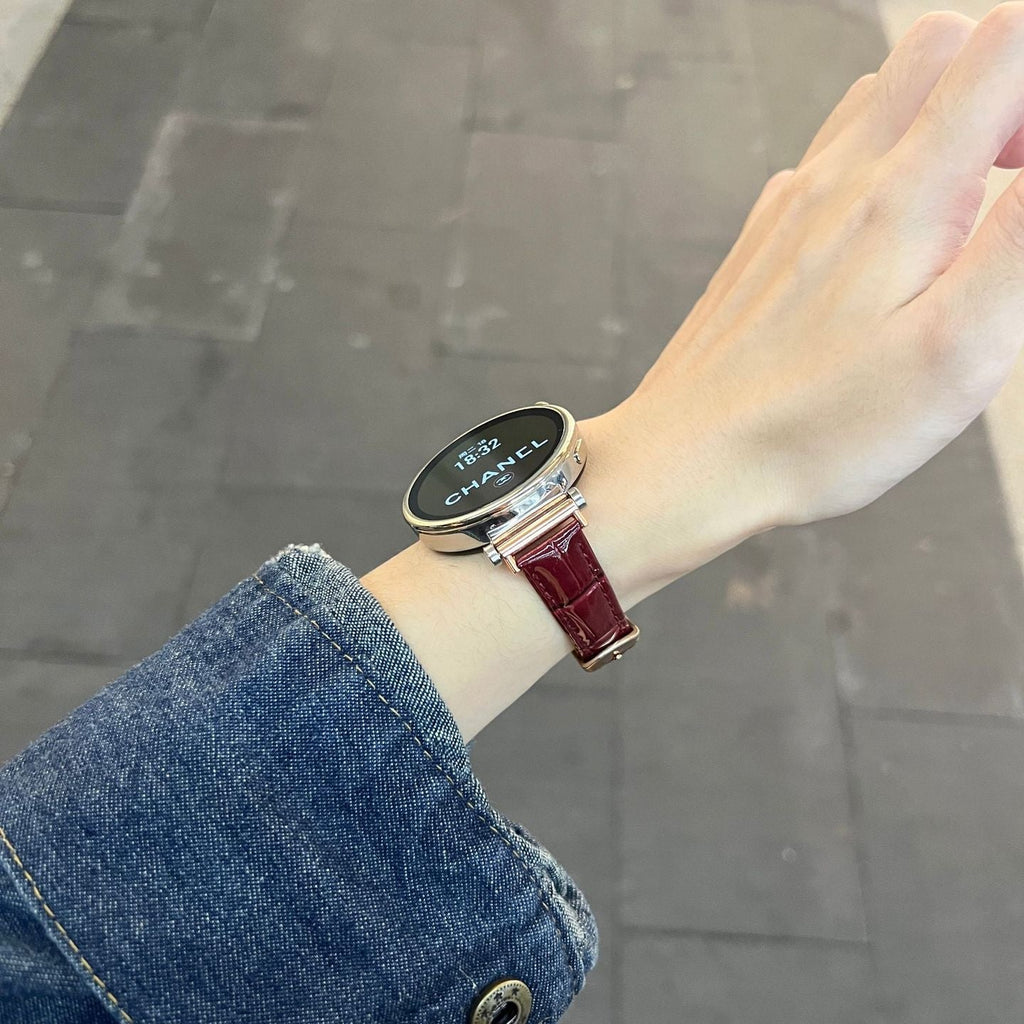 Bracelet montre rouge effet crocodile en simili vegan avec boucle métal doré, porté au poignet féminin.